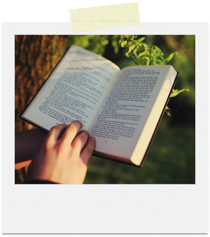 A polaroid of a hand holding an open book