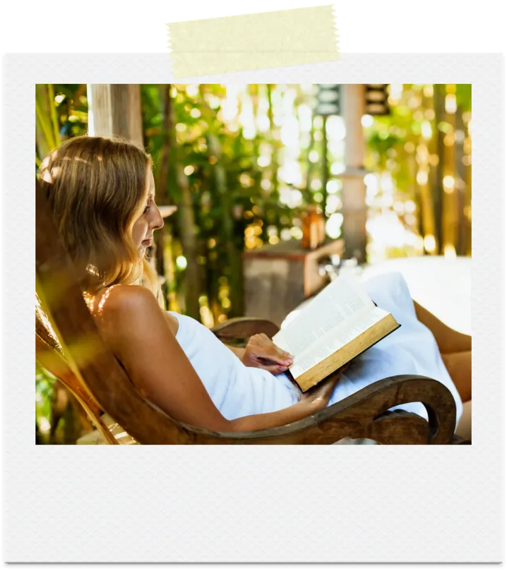 A woman reading on a porch surrounded by greenery